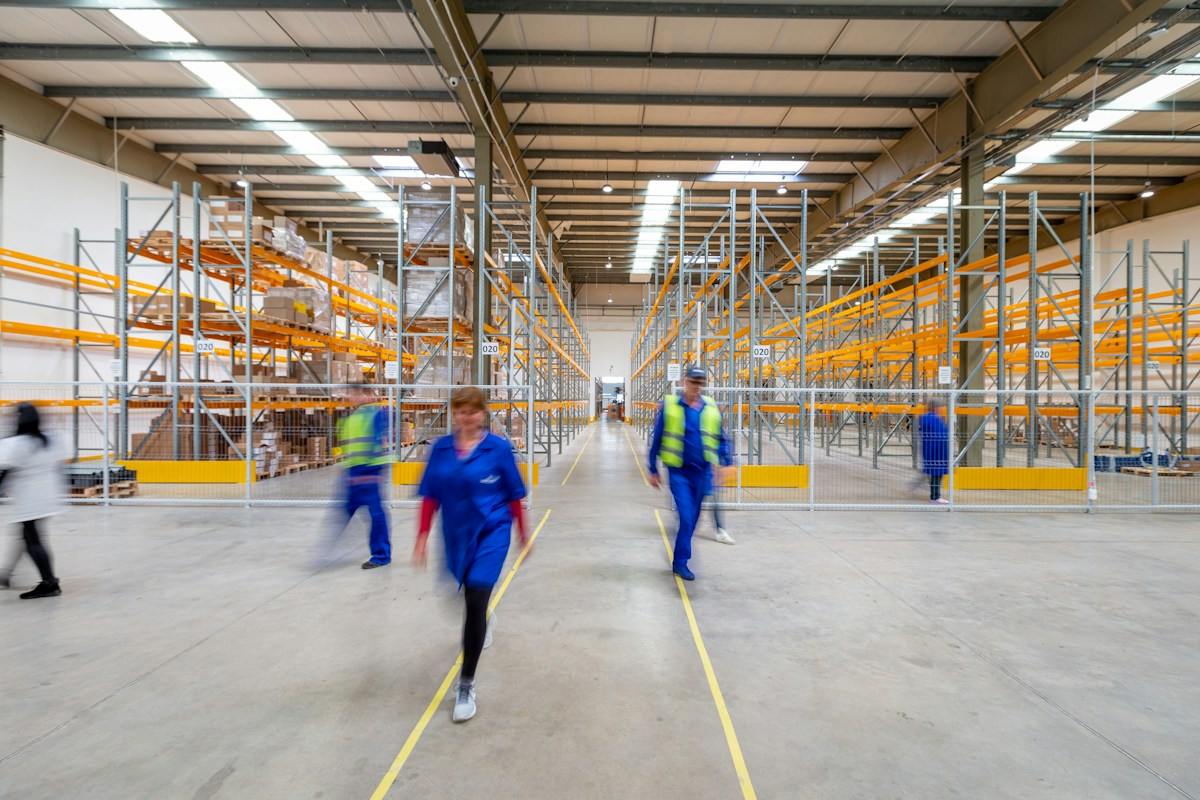 Workers moving through a large warehouse aisle