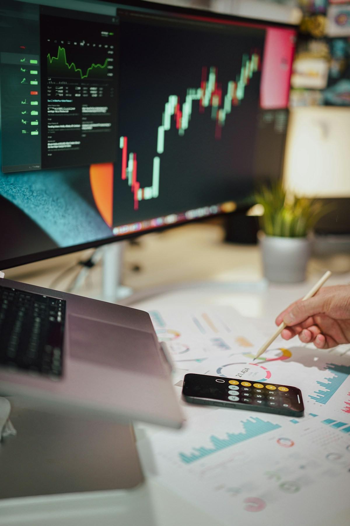 Finance professional annotating a report beside a monitor