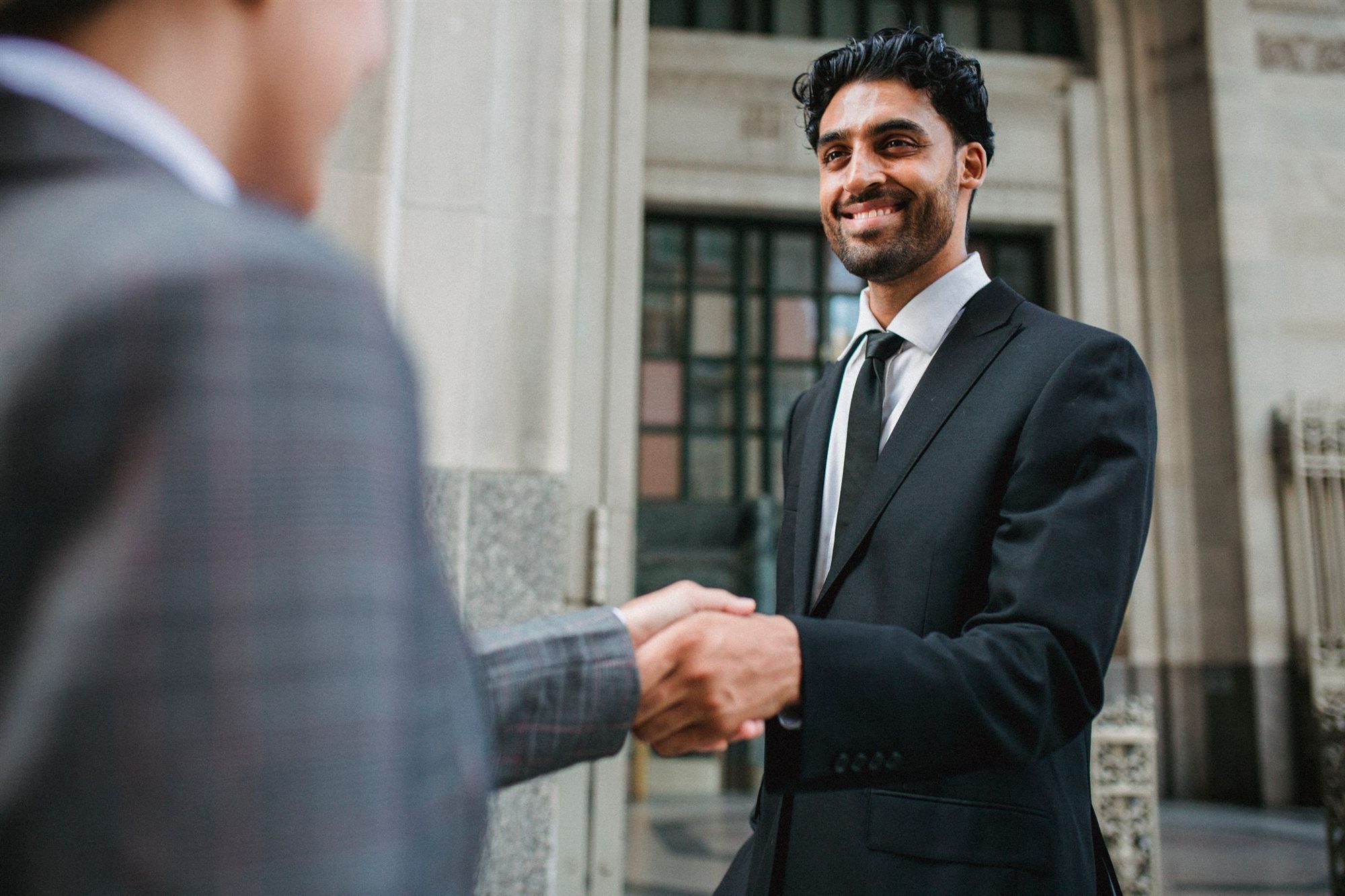 Indian executive smiling as he shakes hands on a deal