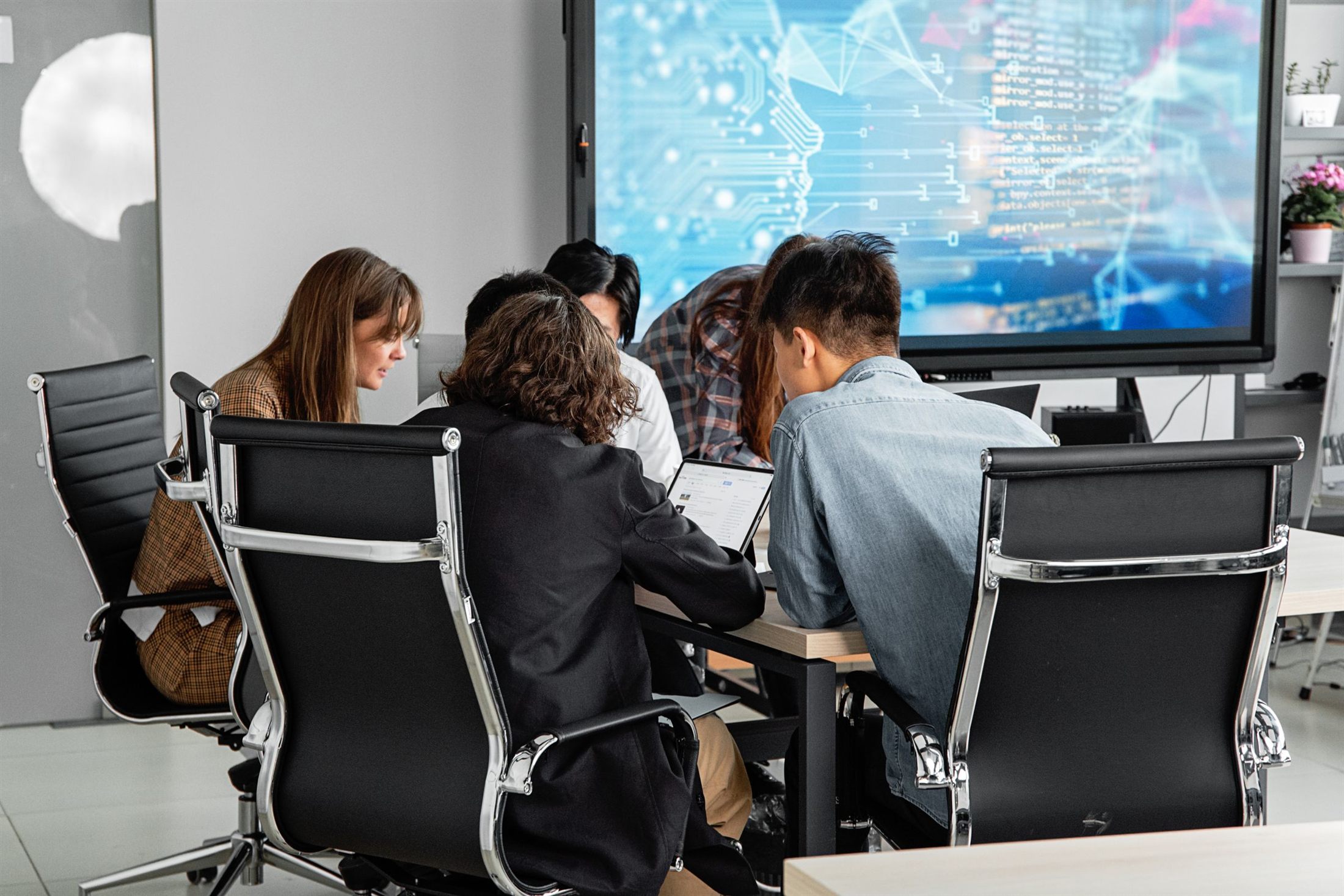 A team working together beneath a large screen showing an AI network visual